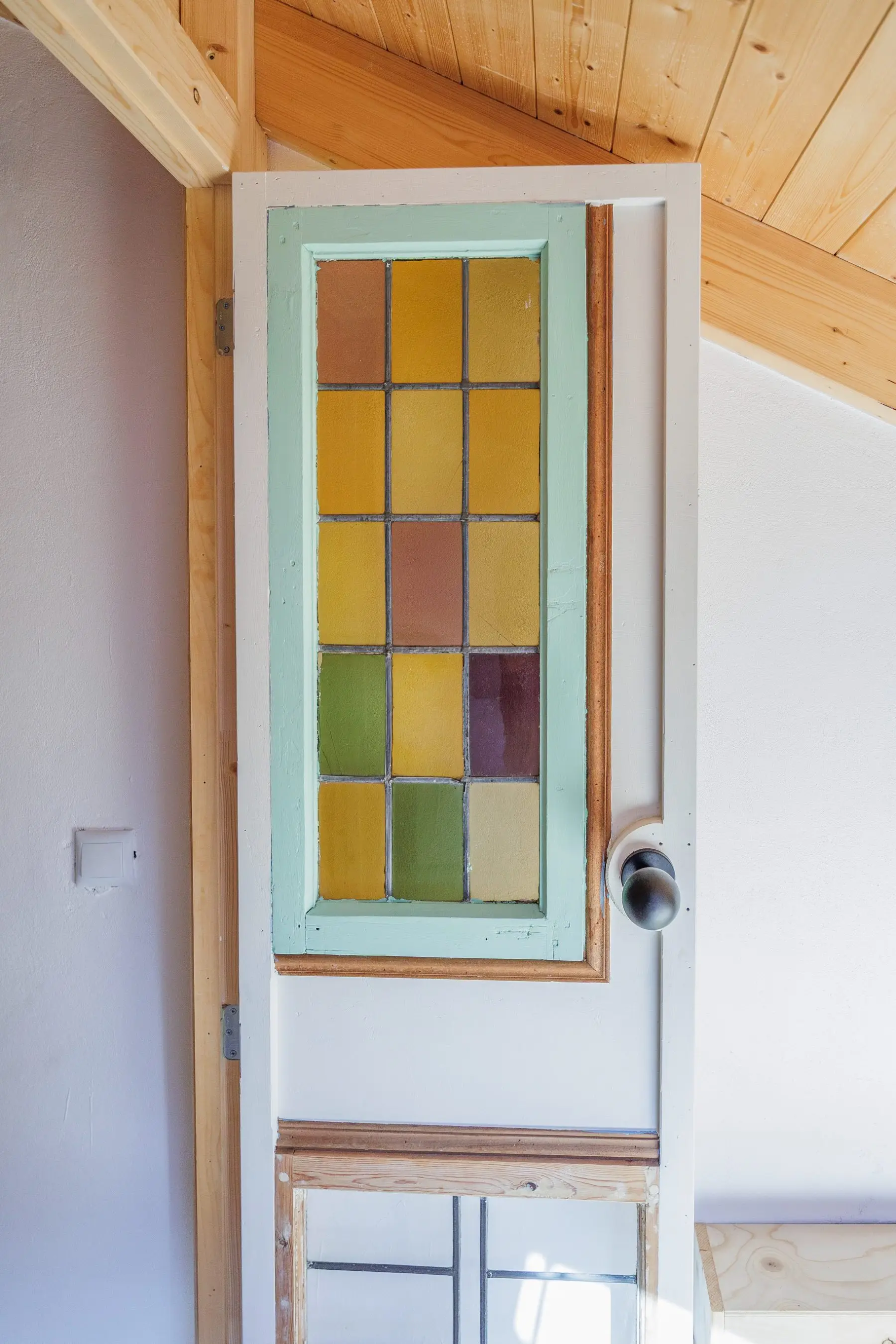 The old door with coloured leaded glass, under the timber roof.