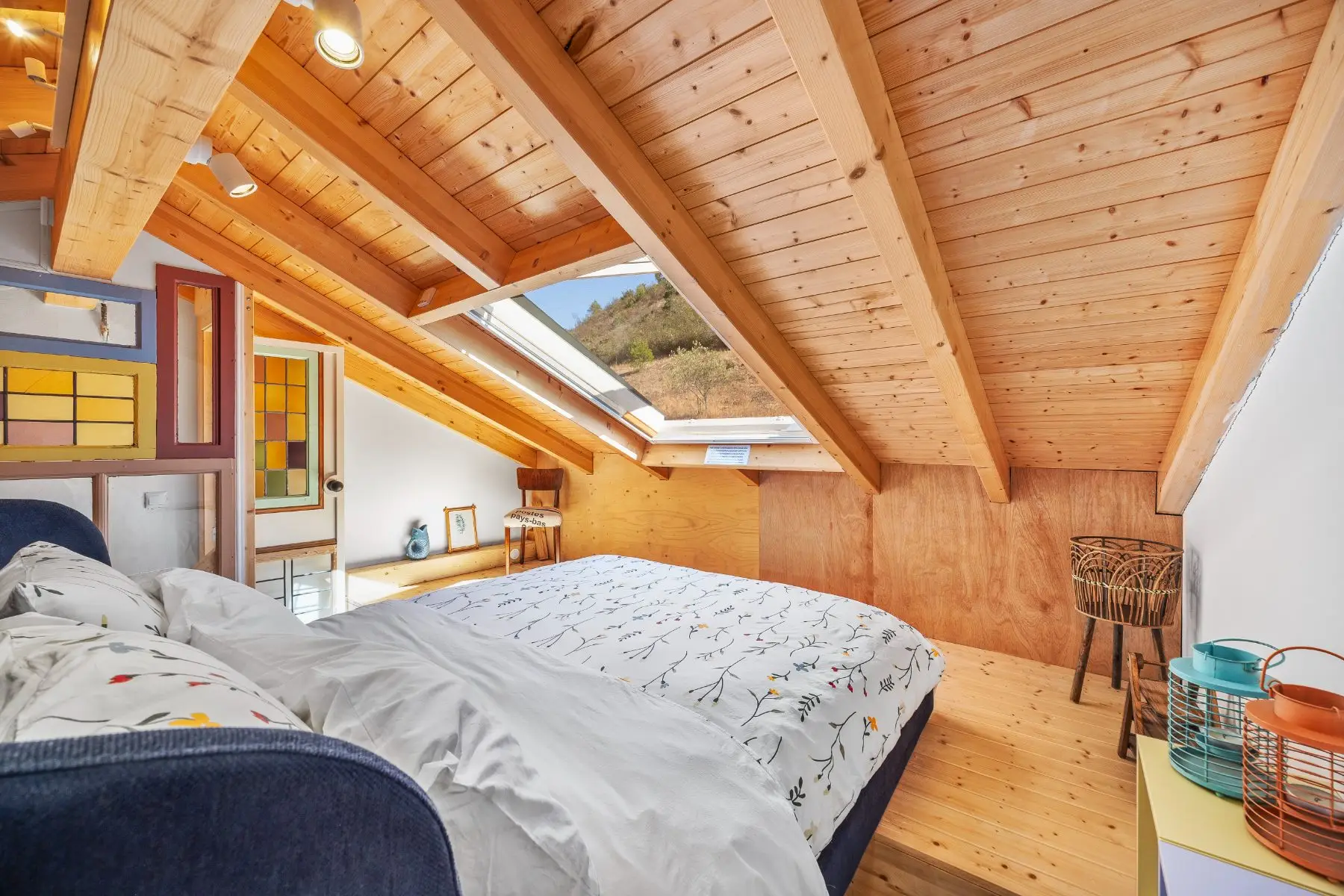 The bed beneath the skylight, pine boarding overhead.