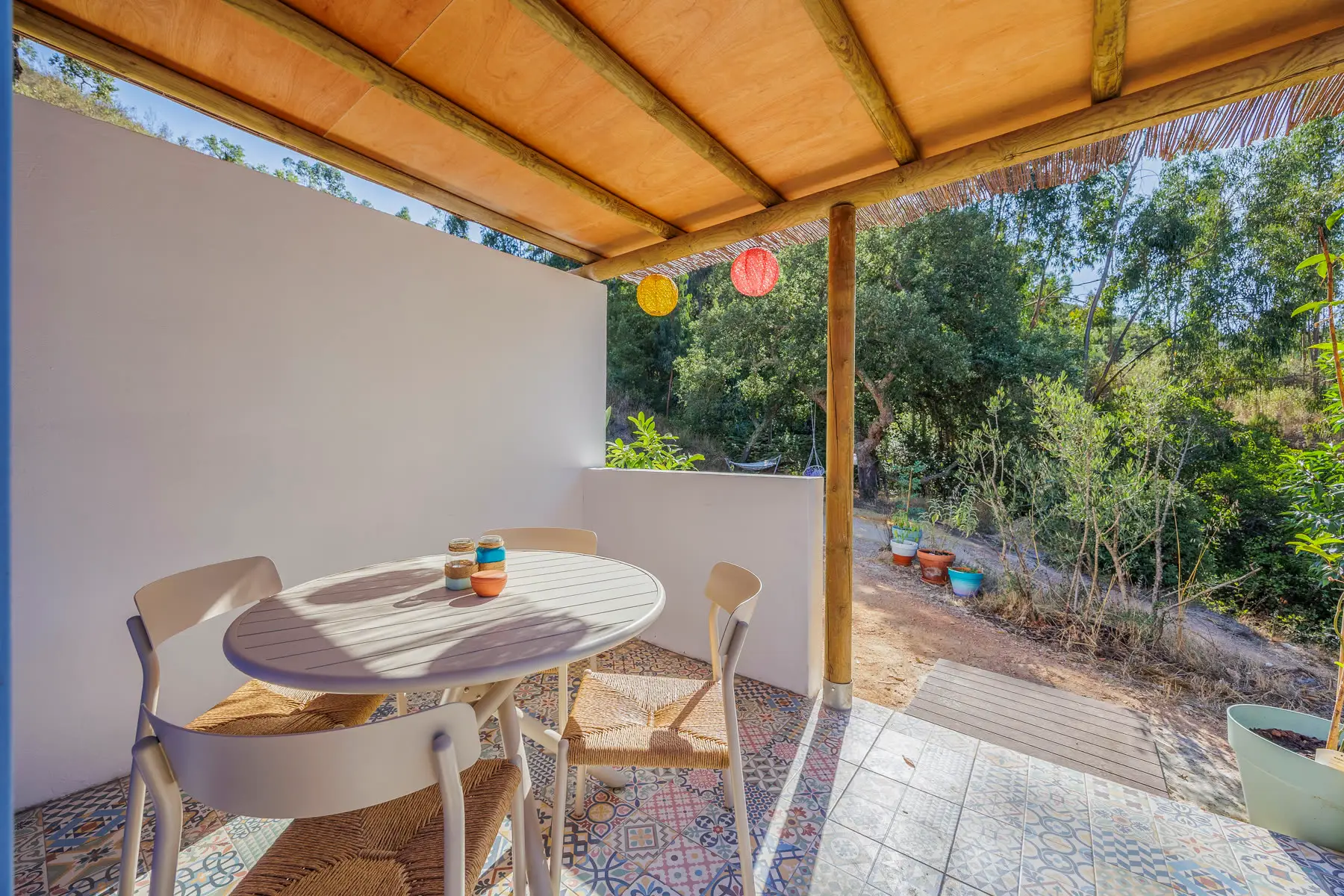 The covered dining table on the terrace, garden behind it.